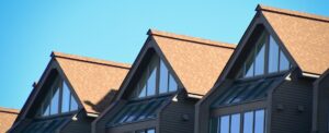 Row of modern gable roofs with large windows on a townhouse building — image for "Roofing Costs Breakdown".