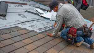 Skilled roofer installing asphalt shingles, ensuring quality roof renovation.