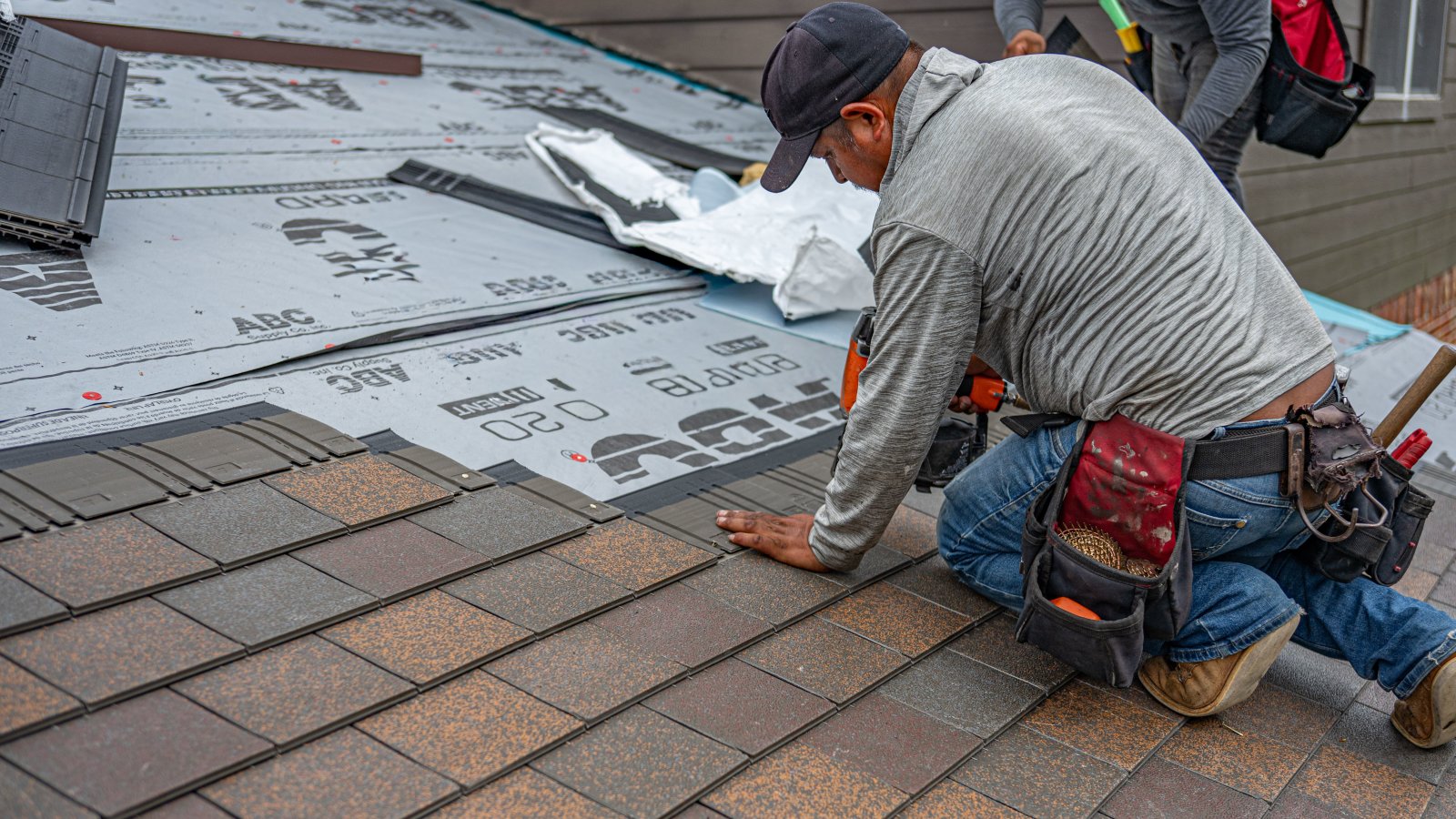 Skilled roofer installing asphalt shingles, ensuring quality roof renovation.
